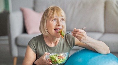 woman eating salad on exercise ball 