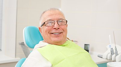 Senior man with glasses smiling in dental chair