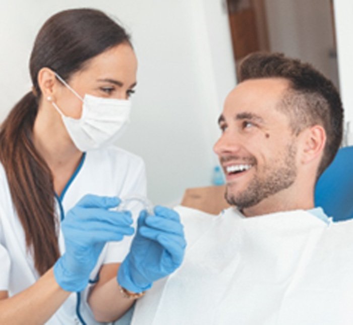 Dentist smiling at patient while holding Invisalign aligners